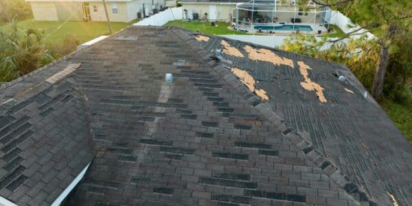 A residential roof with missing and damaged shingles, highlighting the need for repair.